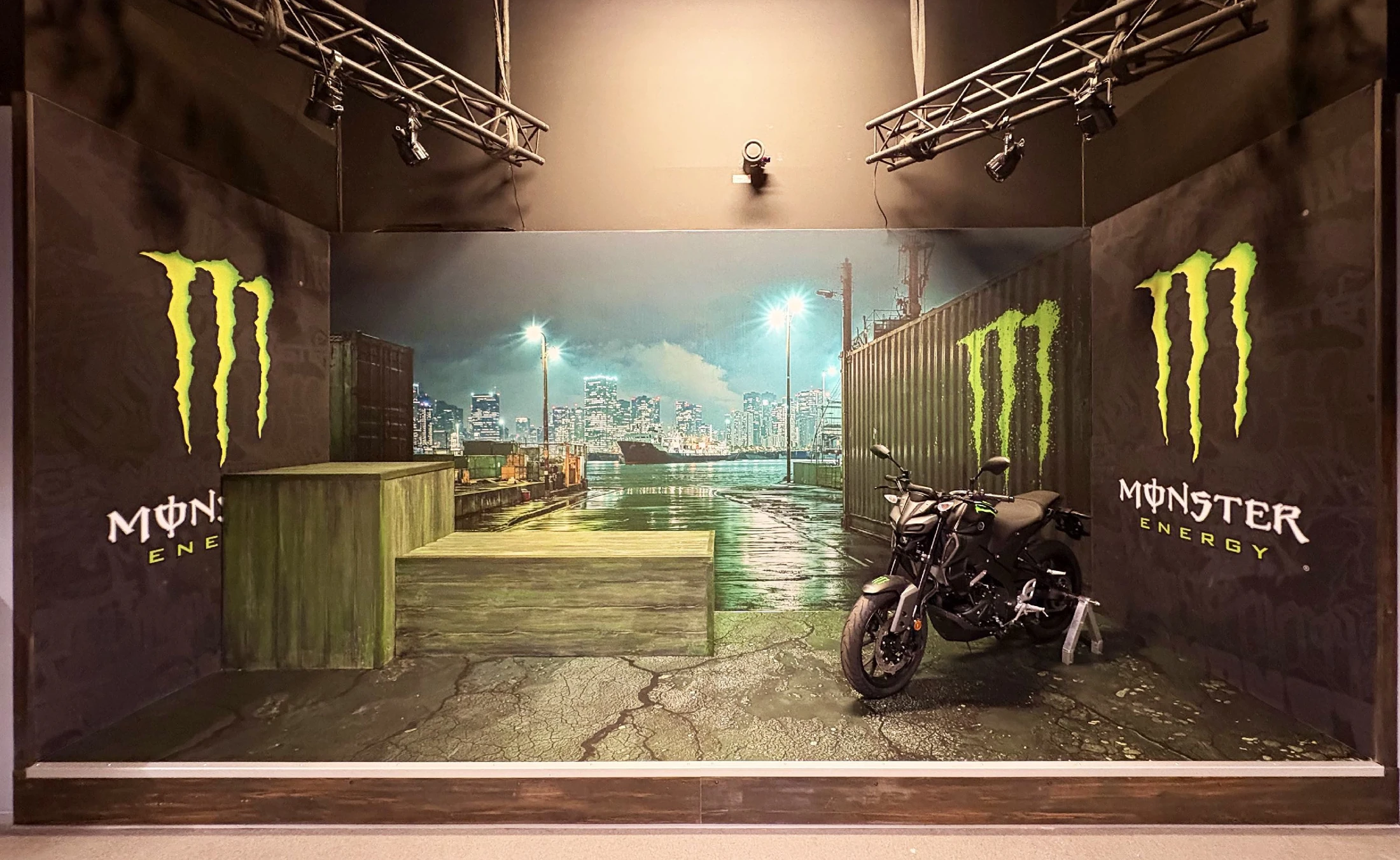 A dramatic Monster Energy installation with a motorcycle and custom industrial construction